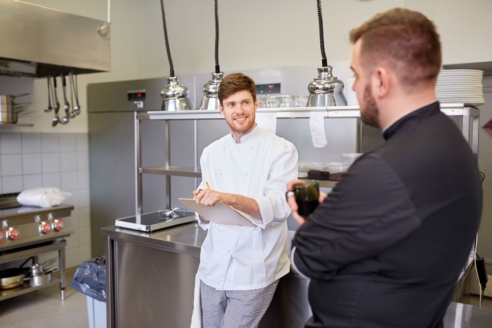 cooking-profession-people-concept-happy-male-chef-cook-having-coffee-break-talking-restaurant-kitchen