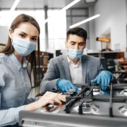 male-salesman-hypermarket-describes-features-gas-stove-female-client-both-wearing-face-masks