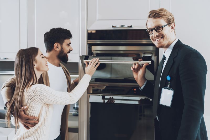 manager-is-showing-built-stove-couple-clients