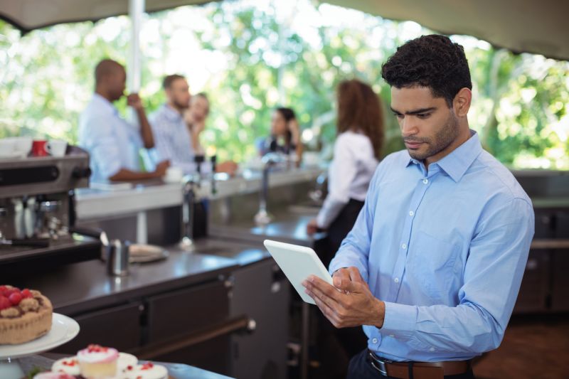 waiter-using-digital-tablet-outdoors-cafe