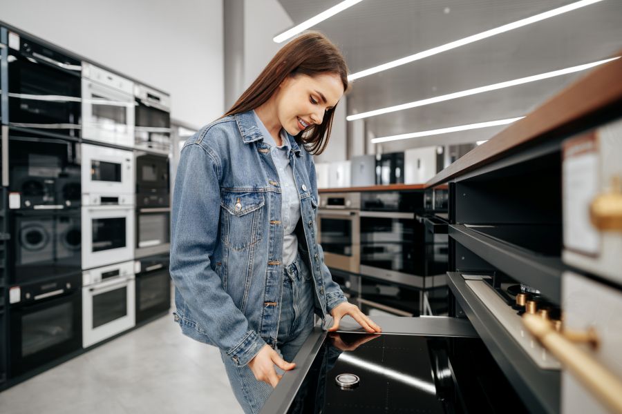 young-brunette-woman-choosing-new-electric-stove-hypermarket