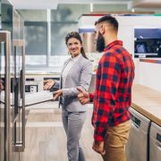 young-man-talking-with-saleswoman-about-refrigerator-he-wants-buy