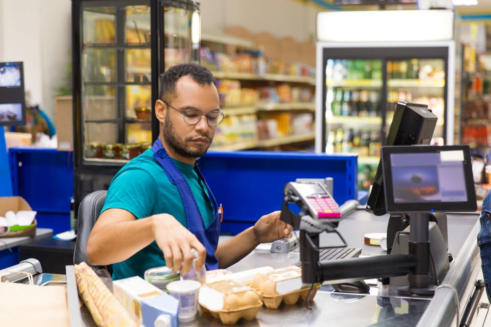 focused-african-american-cashier-scanning-goods-checkout