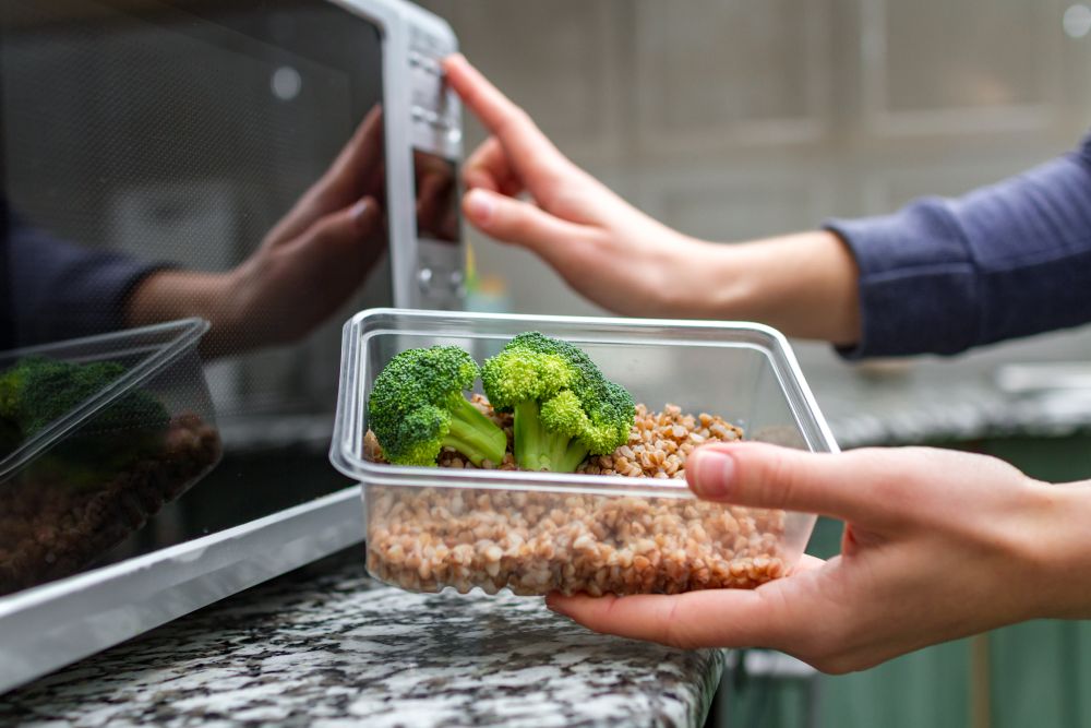 woman-s-hand-going-heat-up-plastic-container-with-broccoli-buckwheat-microwave